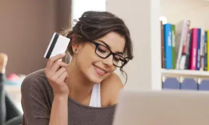 Femme utilisant une carte de crédit pour faire des achats en ligne sur son ordinateur portable, illustrant une campagne Google Shopping.