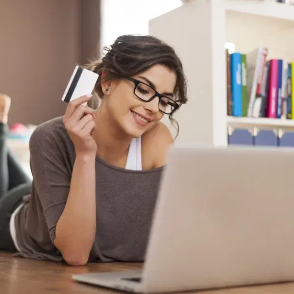Femme utilisant une carte de crédit pour faire des achats en ligne sur son ordinateur portable, illustrant une campagne Google Shopping.