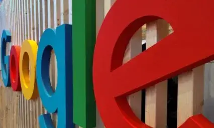 Logo coloré de Google sur un mur en bois, illustrant l'article sur le fonctionnement de Google Ads.
