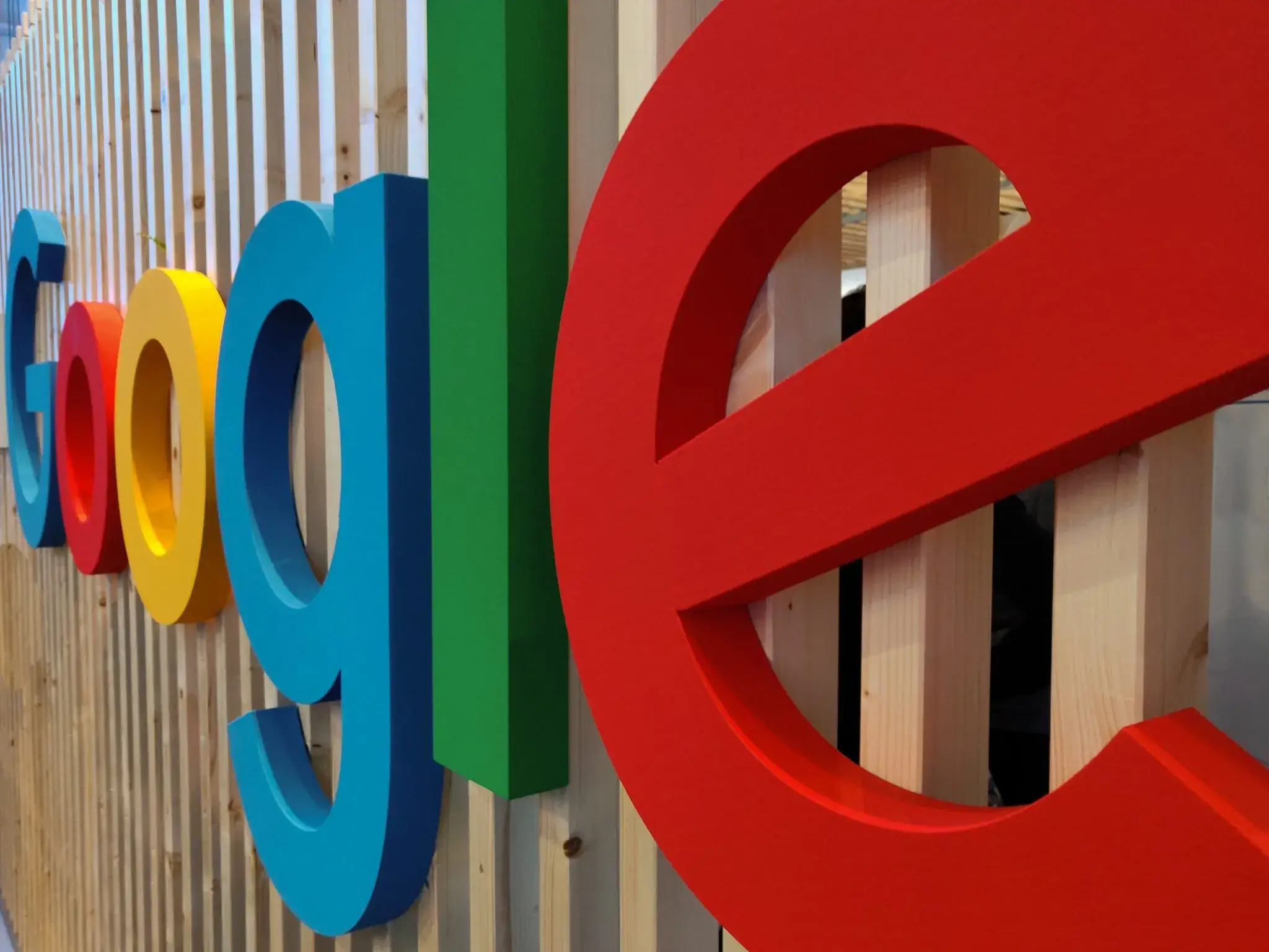 Logo coloré de Google sur un mur en bois, illustrant l'article sur le fonctionnement de Google Ads.