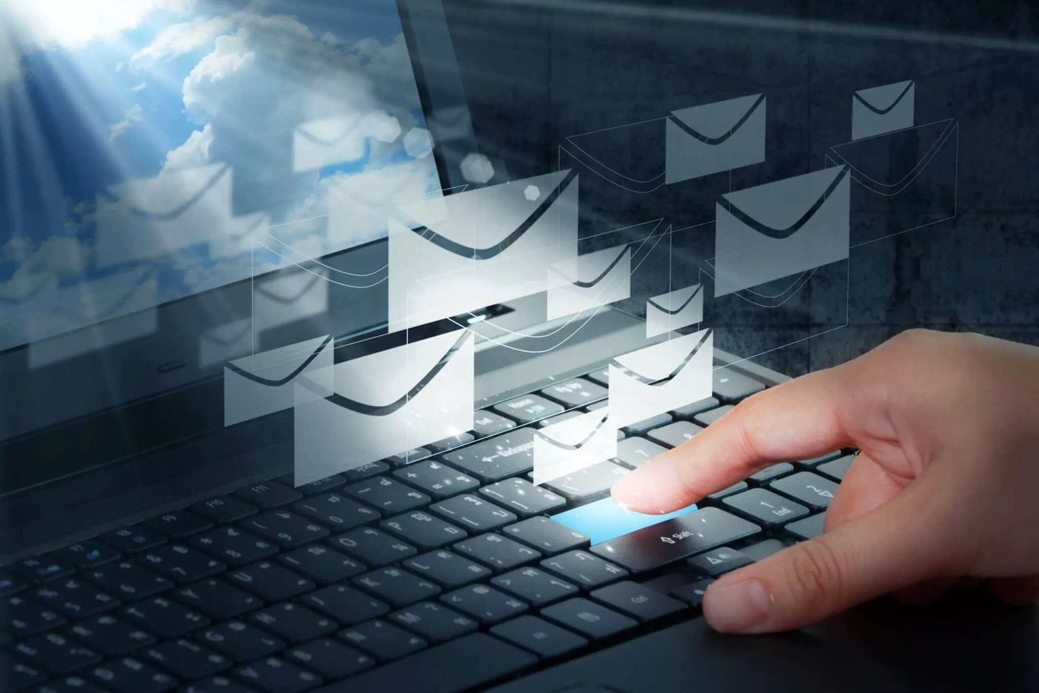 Main appuyant sur une touche de clavier avec des icônes d'e-mails flottants, illustrant une campagne d'emailing.