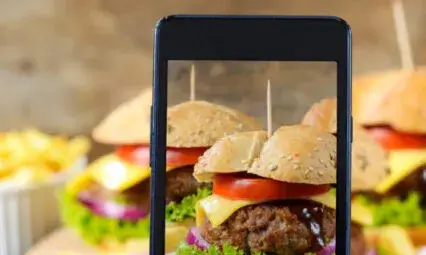 Photo d'un hamburger capturé avec un smartphone, illustrant l'importance du contenu visuel.