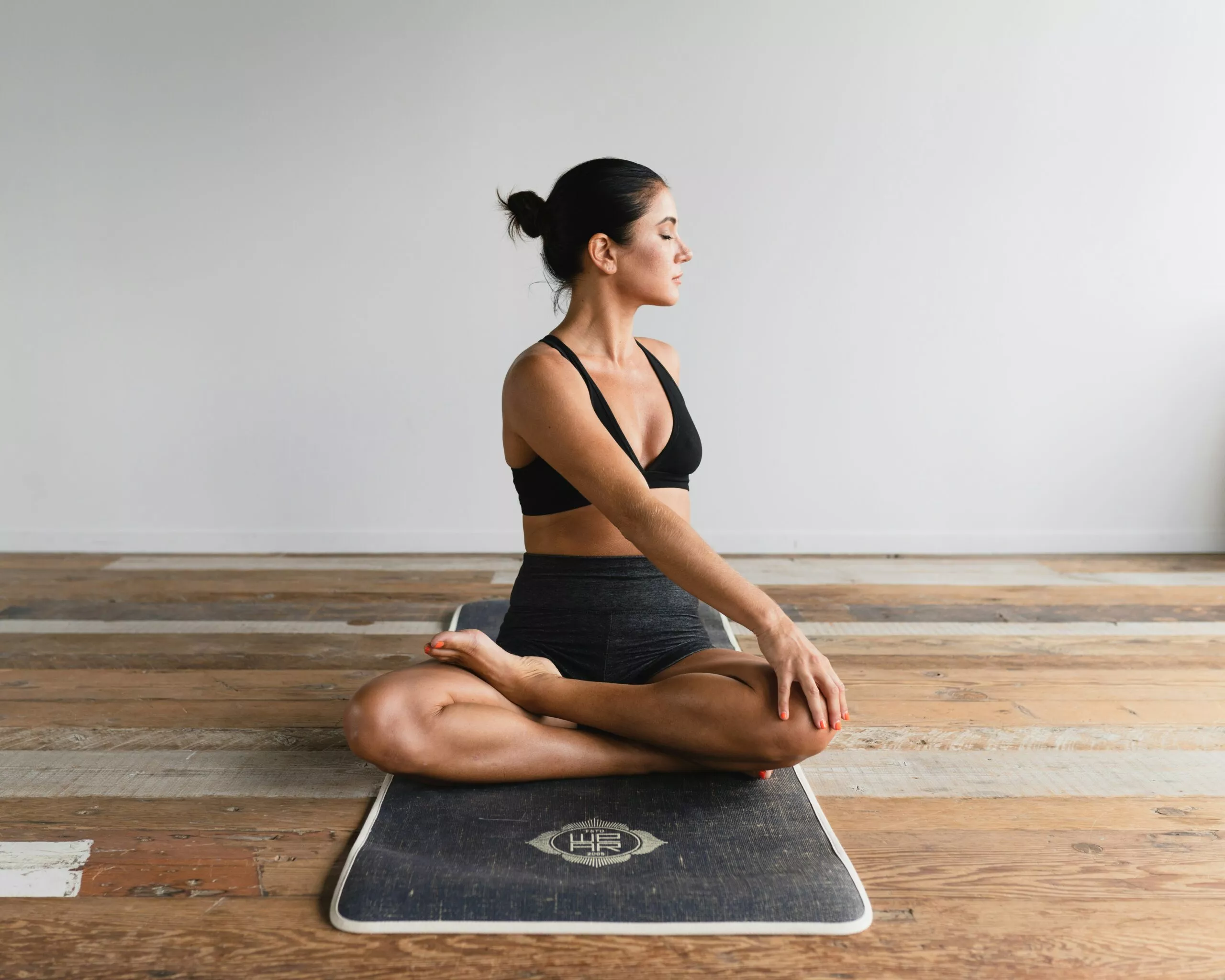 Femme en tenue de sport pratiquant le yoga sur un tapis.