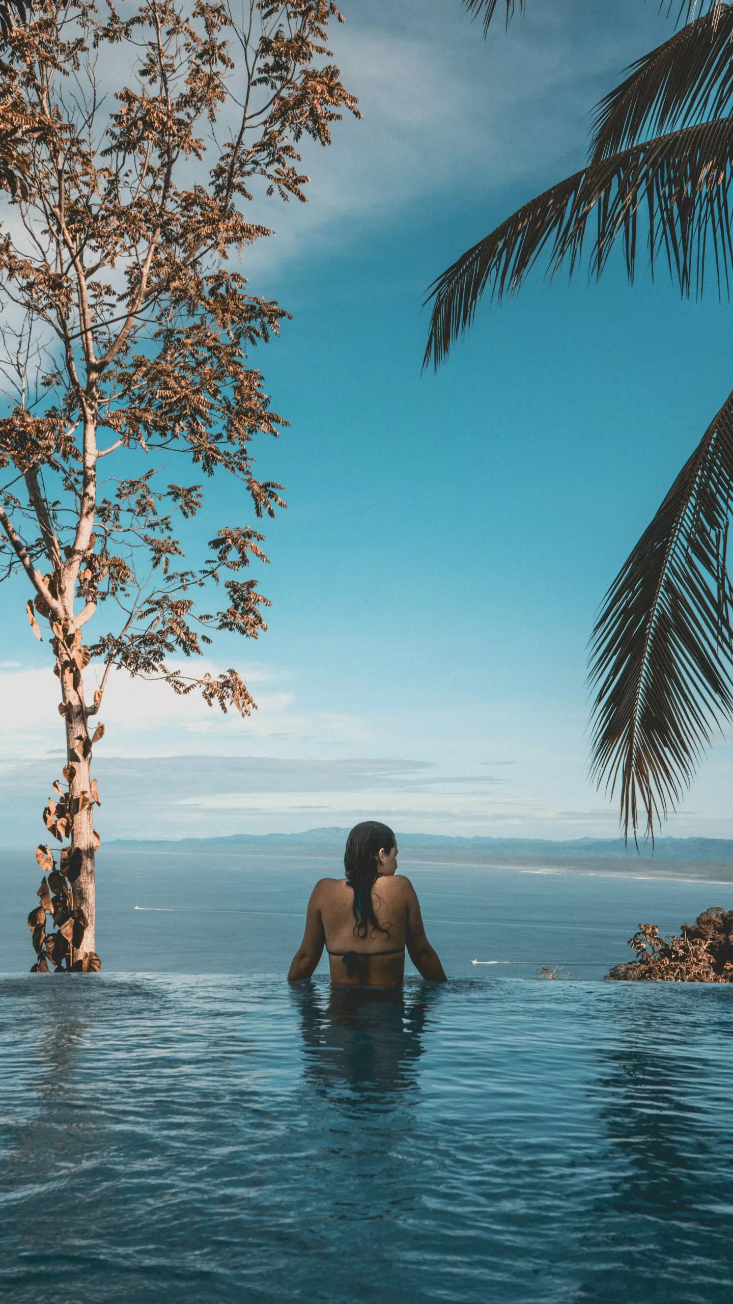 Femme profitant d'une vue panoramique sur la mer depuis une piscine.